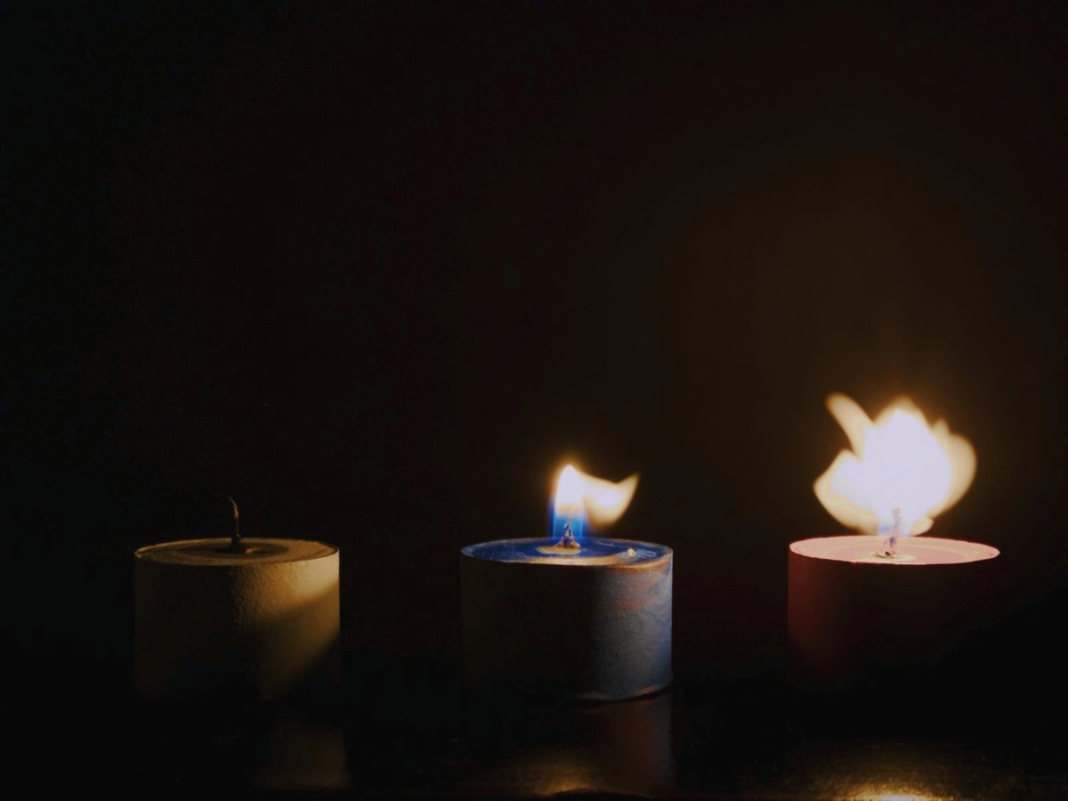 Trois bougies dans une pièce sombre