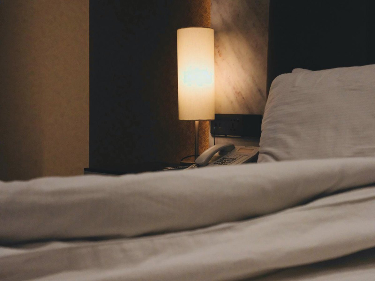 Une lampe de chevet sur des draps froissés