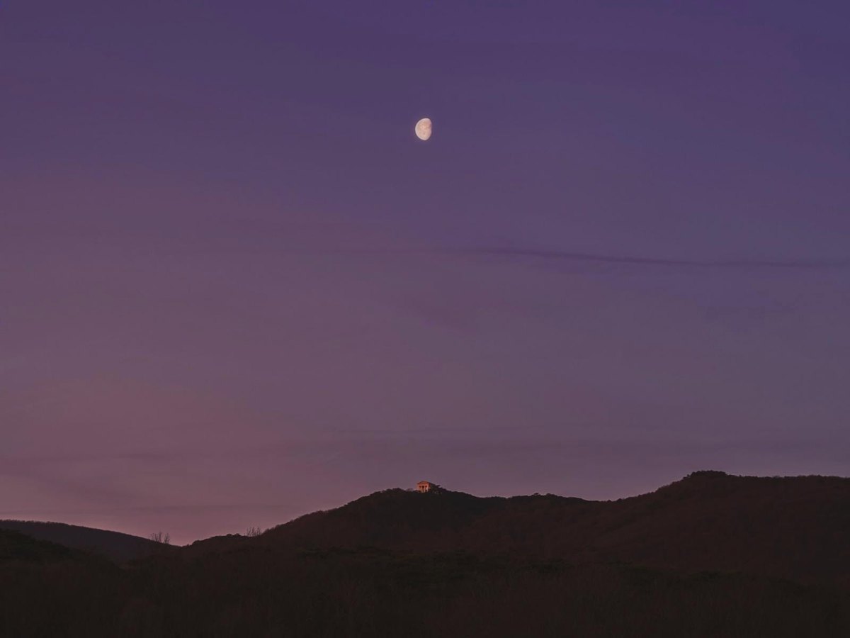 Un petit croissant de lune au-dessus des collines, au crépuscule